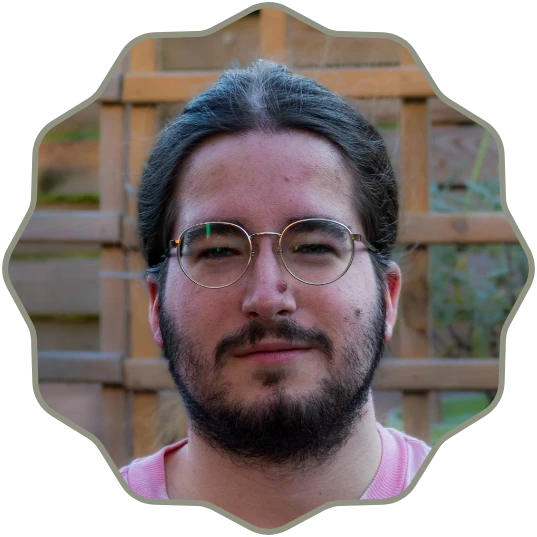 Photo of a man with long dark hair pulled back, wearing round glasses, and sporting a full beard and mustache