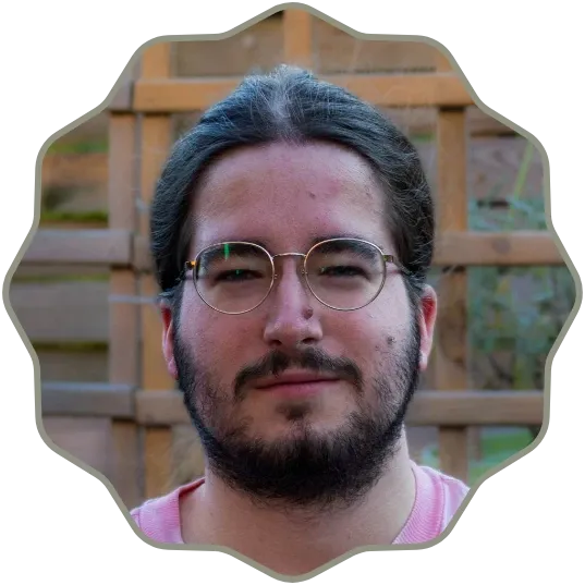 Photo of a man with long dark hair pulled back, wearing round glasses, and sporting a full beard and mustache